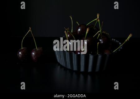 Saftige schwarze Kirschen in einer geriffelten Schale Stockfoto