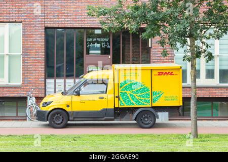 Arnhem, Niederlande - 21. Juli 2021: Elektrischer DHL-Postkurierwagen vor einem Mehrfamilienhaus in Arnhem, Niederlande Stockfoto