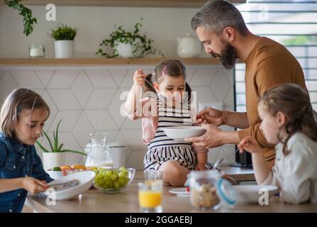 Vater mit drei Töchtern zuhause, beim Frühstück in der Küche. Stockfoto