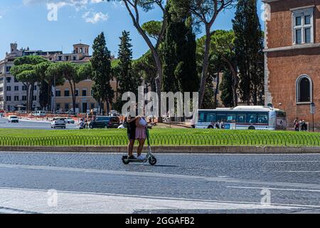 ROM, ITALIEN, GROSSBRITANNIEN. August 2021. Zwei Frauen auf einem Elektroroller auf der Piazza Venezia an einem heißen Tag in Rom. Elektroroller sind in der römischen Hauptstadt populär geworden und werden regelmäßig als Mobilitätstransport eingesetzt. Kredit: amer ghazzal/Alamy Live Nachrichten Stockfoto