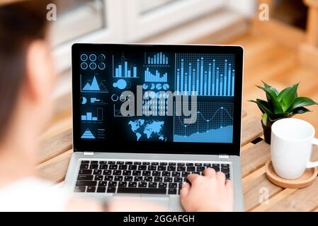 Frau Ist Damit Beschäftigt, Auf Seinem Laptop Neben Dem Kaffeetasse Und Der Pflanze Zu Tippen, Um Von Zu Hause Aus Arbeit Zu Erledigen. Businesswoman Codierung Minicomputer Neben Cap Und Flower Stockfoto