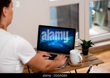 Frau, die ihre Arbeit auf EINEM Laptop neben schönen Pflanzen- und Kaffeebecher arbeitet von zu Hause aus. Girl Making Projects Neben Cup Und Flower Finishing Stockfoto