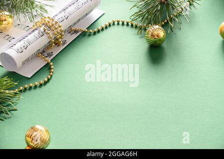 Musikrahmen für Weihnachten Weihnachtslieder und singt geschmückt goldenen Kugeln auf grünem Hintergrund. Blick von oben. Leerzeichen für Text. Stockfoto