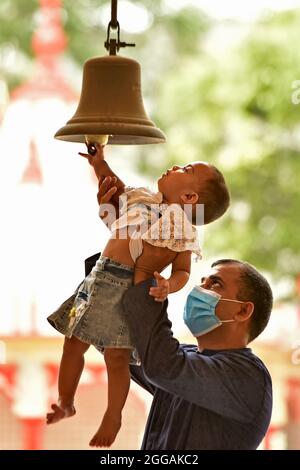 Dhaka. August 2021. Ein Baby klingelt mit Hilfe ihres Vaters in einem Tempel anlässlich von Janmashtami in Dhaka, Bangladesch, am 30. August 2021. Janmashtami ist ein jährliches Fest, das den Geburtstag des Hindu-gottes Krishna feiert. Quelle: Xinhua/Alamy Live News Stockfoto