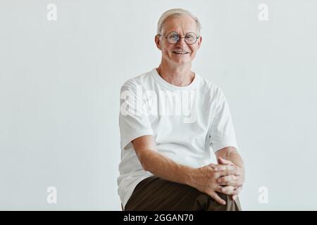 Minimales Porträt eines lächelnden älteren Mannes, der auf die Kamera schaut, während er vor weißem Hintergrund posiert, Kopierraum Stockfoto