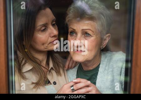 Nahaufnahme des Porträts einer traurigen älteren Mutter mit einer erwachsenen Tochter, die sich zu Hause umarmt. Stockfoto