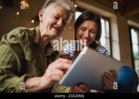 Porträt einer glücklichen älteren Mutter mit einer erwachsenen Tochter im Haus, mit Tablet. Stockfoto