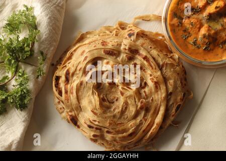 Parotta oder Porotta, ein geschichtetes Fladenbrot aus Maida. Dieser flockige Bändchenpfannkuchen ist ein Favorit von Kerala. Shot mit Butter Hähnchen aus gegrilltem Lch Stockfoto