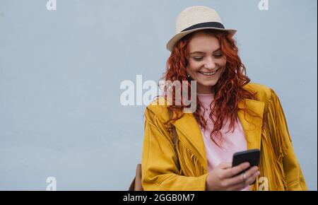 Junge Frau Tourist im Freien vor weißem Hintergrund auf Reise in der Stadt, mit dem Smartphone. Stockfoto