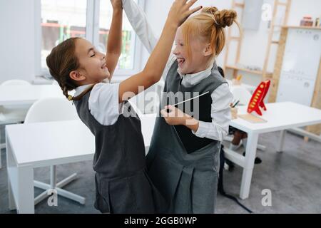 Zwei Grundschüler, die in einer Schule einen freundlichen Kampf führen. In einem hellen Schulzimmer. Stockfoto