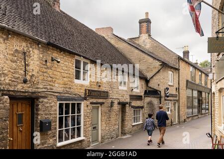 Ein Mann und ein Junge gehen die Church Street in Stow on the Wold entlang, umgeben von traditionellen Cotswold Kalksteingebäuden. Gloucestershire, Großbritannien Stockfoto