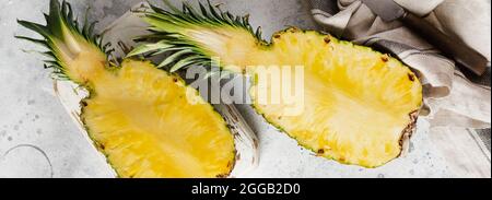 Frische Ananas in zwei Teile geschnitten auf grauem Beton alten Hintergrund. Sommerkonzept. Kreative, flache Lay-Version mit Platz für Kopien. Draufsicht. Stockfoto