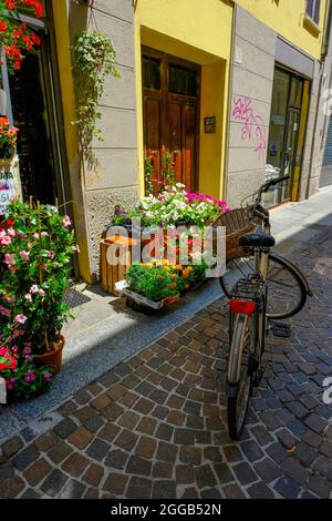 Fahrrad mit Korb auf der Straße in der Nähe des Blumenladens. Europäische Straßen. Parma, Italien, Reisen, vertikal, Stockfoto