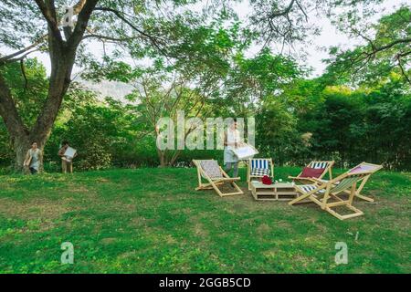 KANCHANABURI, THAILAND - JANUAR 11,2020 : ein nicht identifizierter asiatischer Kellner bereitet Liegestühle für die Gäste zu, um im Garten von Mulberry zu sitzen und sich zu entspannen Stockfoto