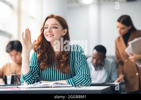 Porträt einer lächelnden Schülerin, die im Klassenzimmer die Hand hebt Stockfoto