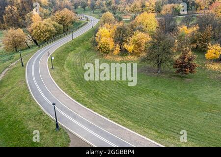 Kurvenreiche Fahrradstraße durch den malerischen Herbstpark. Luftaufnahme von oben Stockfoto