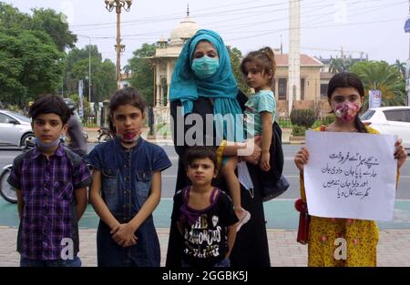 Frau aus Shahdara hält Plakate, die Kinder zum Verkauf beschreiben, während sie ihre Kinder während einer Protestdemonstration vor dem Gebäude der Punjab-Versammlung in Lahore am Montag, dem 30. August 2021, verkaufen möchte. Stockfoto