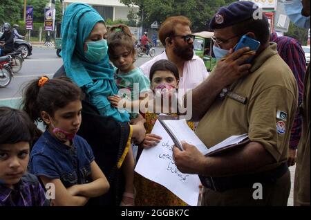 Frau aus Shahdara hält Plakate, die Kinder zum Verkauf beschreiben, während sie ihre Kinder während einer Protestdemonstration vor dem Gebäude der Punjab-Versammlung in Lahore am Montag, dem 30. August 2021, verkaufen möchte. Stockfoto