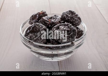 Süße Bio-Pflaumen in einer Glasschale, aus nächster Nähe, auf einem weißen Tisch. Stockfoto