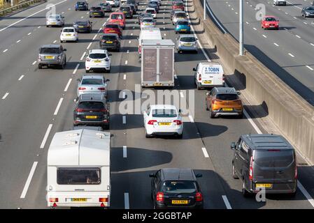 Abschnitt der Autobahn M25 in Longford in der Nähe des Flughafens Heathrow, Großbritannien, der an einem Sommerwochenende an den Feiertagen im August voll mit Verkehr ist. Wohnwagen und Autos Stockfoto