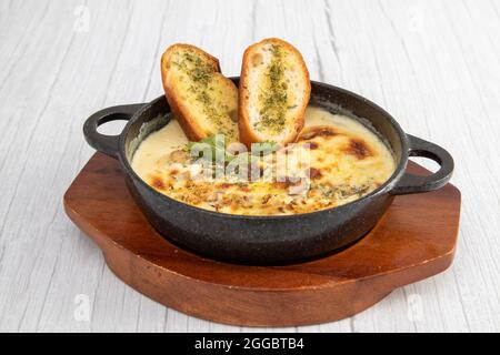 Eine schmackhafte, klare Suppe aus frischen Champignons, die mit gehacktem Knoblauch, frischem Basilikum und Parmesankäse auf der Seite angebraten wird. Stockfoto