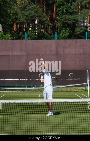 Sportler, die Tennis spielen, in der Nähe von verschwommenem Netz auf dem Platz Stockfoto