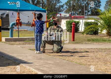 Rota, Spanien. August 2021. Ein Seemann der US-Marine spielt mit einem afghanischen Kind, das von Kabul zur Naval Air Station Rota am 29. August 2021 in Rota, Spanien, evakuiert wurde. NAS Rota stellt im Rahmen der Operation Allies Refuge eine vorübergehende Unterkunft für Evakuierte aus Afghanistan bereit. Quelle: Planetpix/Alamy Live News Stockfoto