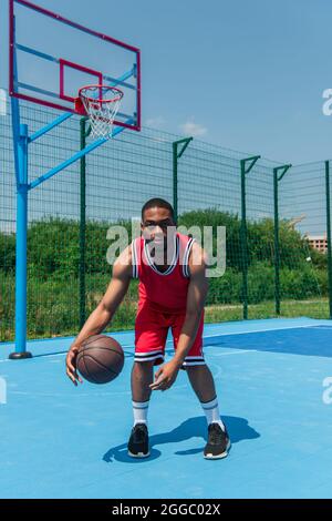 afroamerikanischer Mann spielt Basketball und schaut in die Kamera Stockfoto