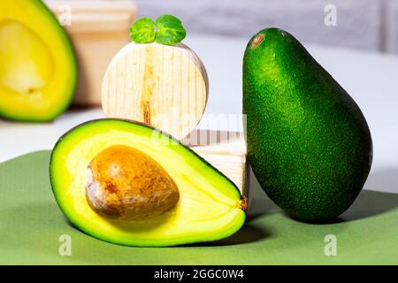 Hälften von reifen Avocado und Micro Green auf Holzbrett serviert auf dem Tisch, weißer Hintergrund, gesunde ölige Lebensmittel, Keto-Diät, Nahaufnahme. Stockfoto