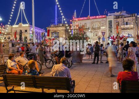 MOSTA, MALTA - 15. Aug 2021: Menschen entspannen, unterhalten und Mühlen auf dem Kirchplatz anlässlich des Festes der Himmelfahrt der Muttergottes. Mosta, Mal Stockfoto