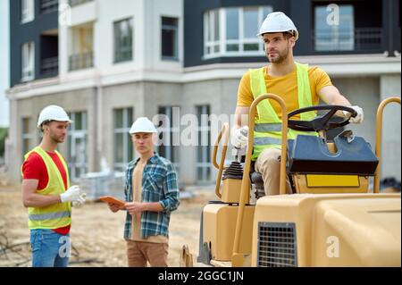 Drei attraktive, qualifizierte Bauarbeiter in Harthüten auf der Baustelle Stockfoto