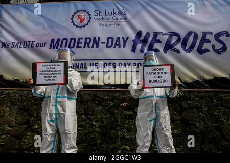 Metro Manila, Philippinen. August 2021. Mitarbeiter des Gesundheitswesens tragen während eines Protestes zum National Heroes Day vor dem St. Luke's Medical Center in Quezon City Schilder. Die Gruppe forderte die Regierung auf, Mittel für Leistungen und einen angemessenen Schutz für medizinisches Personal freizugeben, das angesichts der Zunahme der COVID-19-Fälle im Land weiterhin gefährdet ist. Kredit: Majority World CIC/Alamy Live Nachrichten Stockfoto