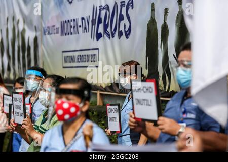 Metro Manila, Philippinen. August 2021. Mitarbeiter des Gesundheitswesens tragen während eines Protestes zum National Heroes Day vor dem St. Luke's Medical Center in Quezon City Schilder. Die Gruppe forderte die Regierung auf, Mittel für Leistungen und einen angemessenen Schutz für medizinisches Personal freizugeben, das angesichts der Zunahme der COVID-19-Fälle im Land weiterhin gefährdet ist. Kredit: Majority World CIC/Alamy Live Nachrichten Stockfoto