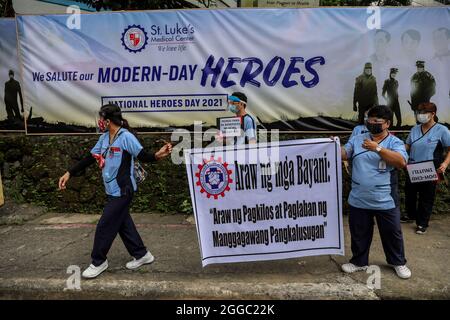 Metro Manila, Philippinen. August 2021. Mitarbeiter des Gesundheitswesens tragen während eines Protestes zum National Heroes Day vor dem St. Luke's Medical Center in Quezon City Schilder. Die Gruppe forderte die Regierung auf, Mittel für Leistungen und einen angemessenen Schutz für medizinisches Personal freizugeben, das angesichts der Zunahme der COVID-19-Fälle im Land weiterhin gefährdet ist. Kredit: Majority World CIC/Alamy Live Nachrichten Stockfoto