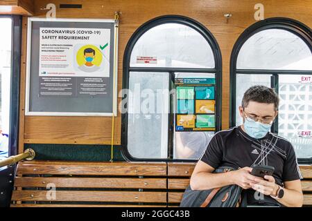 Miami Beach Florida kostenlose Trolley öffentlichen Verkehrsmitteln tragen Maske Nachricht Covid-19 Gesundheit Krise Pandemie Coronavirus CDC Anleitung Hispanic Mann Stockfoto