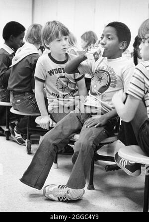 Austin Texas USA, 1984: Patrick Skeaton, der sein rechtes Bein wegen Spina bifida verlor, interagiert mit Klassenkameraden in der Schulcafeteria der Wooten Elementary. Später wurde er mit einer Beinprothese ausgestattet. Teil einer erweiterten Fotofunktion. ©Bob Daemmrich Stockfoto