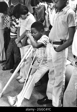 Austin Texas USA, 1984: Der schwarze Schüler Patrick Skeaton, der sein rechtes Bein aufgrund einer Spina bifida verlor, benutzt Holzkrücken, um an der Wooten Elementary School in Austin, Texas, zu kommen, während er in den regulären Unterricht integriert wird. Später wurde er mit einer Beinprothese ausgestattet. Teil einer erweiterten Fotofunktion. ©Bob Daemmrich Stockfoto