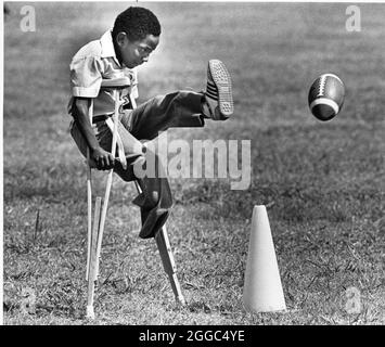 Austin Texas USA, 1984: Der schwarze Schüler Patrick Skeaton, der sein rechtes Bein aufgrund einer Spina bifida verlor, benutzt Holzkrücken, um an der Wooten Elementary School in Austin, Texas, zu kommen, während er in den regulären Unterricht integriert wird. Später wurde er mit einer Beinprothese ausgestattet. Teil einer erweiterten Fotofunktion. ©Bob Daemmrich Stockfoto