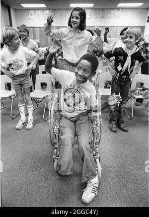 Austin Texas USA, 1984: Der schwarze Schüler Patrick Skeaton, der sein rechtes Bein aufgrund einer Spina bifida verlor, interagiert mit Klassenkameraden der Wooten Elementary School, während er in den regulären Unterricht einbezogen wird. Später wurde er mit einer Beinprothese ausgestattet. Teil einer erweiterten Fotofunktion. ©Bob Daemmrich Stockfoto