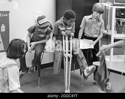 Austin Texas USA, 1984: Der schwarze Schüler Patrick Skeaton, der sein rechtes Bein aufgrund einer Spina bifida verlor, benutzt Holzkrücken, um an der Wooten Elementary School in Austin, Texas, zu kommen, während er in den regulären Unterricht integriert wird. Später wurde er mit einer Beinprothese ausgestattet. Teil einer erweiterten Fotofunktion. ©Bob Daemmrich Stockfoto