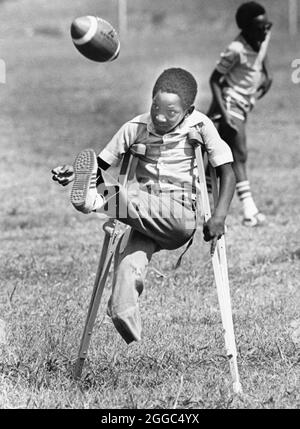 Austin Texas USA, 1984: Der schwarze Schüler Patrick Skeaton, der sein rechtes Bein aufgrund einer Spina bifida verlor, benutzt Holzkrücken, um an der Wooten Elementary School in Austin, Texas, zu kommen, während er in den regulären Unterricht integriert wird. Später wurde er mit einer Beinprothese ausgestattet. Teil einer erweiterten Fotofunktion. ©Bob Daemmrich Stockfoto