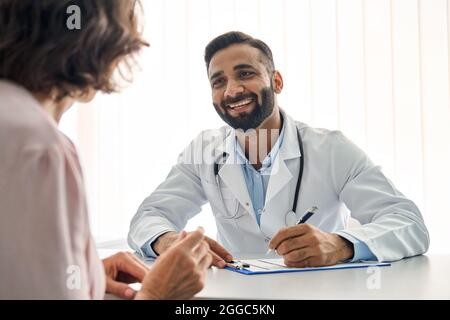 Glücklicher indischer Arzt, der Termin mit weiblicher Patientin im Klinikkrankenhaus hat. Stockfoto