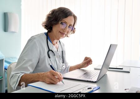 Leitende Ärztin in der Klinik, die sich per Fernzugriff mit einem pc-Laptop-Computer berät. Stockfoto