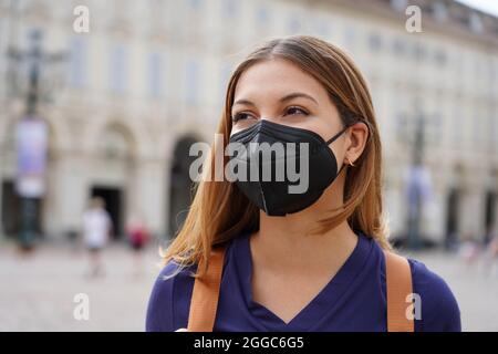 Porträt eines Studenten Mädchen trägt eine schützende KN95 FFP2 schwarze Maske zu Fuß in der Stadt Straße Stockfoto