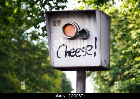 Steuerung der Verkehrsgeschwindigkeit durch ein Radarmesssystem. Blitzer wird mit den Worten „Käse!“ besprüht und bittet Sie, zu lächeln. Dortmund, Deutschland --- Geschwindigkeitsüberwachung. Blitzer ist mit der Aufschrift *Cheese!*, besprüht, mit der Bitte zu lächeln. Dortmund, 30.08.2021. Stockfoto
