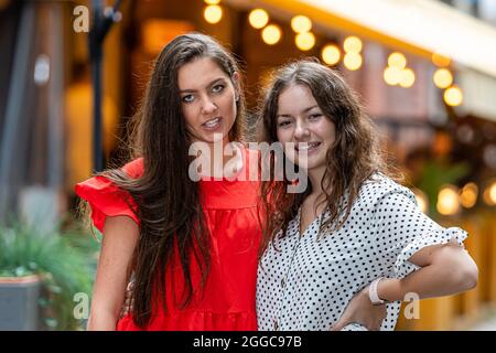 Zwei niedliche und wunderschöne Frauen stehen zusammen auf verschwommenem Hintergrund mit Bokeh-Licht Stockfoto