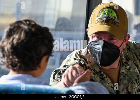 MARINESTÜTZPUNKT ROTA, Spanien (Aug 29, 2021) EIN Seemann aus der nach vorne entsendeten Abteilung des Regionalen Wartungszentrums (FDRMC) Rota interagiert mit einem Kind, das in einem Bus der Naval Station (NAVSTA) Rota aus Afghanistan evakuiert wurde, am 29. August 2021. NAVSTA Rota unterstützt derzeit die Mission des Außenministeriums, um die sichere Ausreise und Umsiedlung von US-Bürgern, Empfängern von Sondervisa für Immigration und gefährdeten Bevölkerungsgruppen aus Afghanistan zu erleichtern. (USA Navy Foto von Yeoman 3rd Class Sarah Weaver) Stockfoto