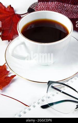Warmes kariertes Karo und eine Tasse heißen Espresso-Kaffee auf weißem Hintergrund. Hallo Herbstkonzept. Rote Blätter fallen und trinken für kaltes Wetter. Kopieren Sie den SPAC Stockfoto