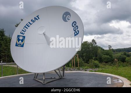 Transinne, Wallonien, Belgien - 10. August 2021: Euro Space Centre. Modell der Eutelsat-Antenne auf grüner Domäne unter regnerischer Wolkenlandschaft. Stockfoto