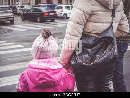 POZNAN, POLEN - 18. Oktober 2016: Eine Mutter mit Ledertasche, die die Hand ihres Kindes vor einer Zebrakreuzung hält Stockfoto